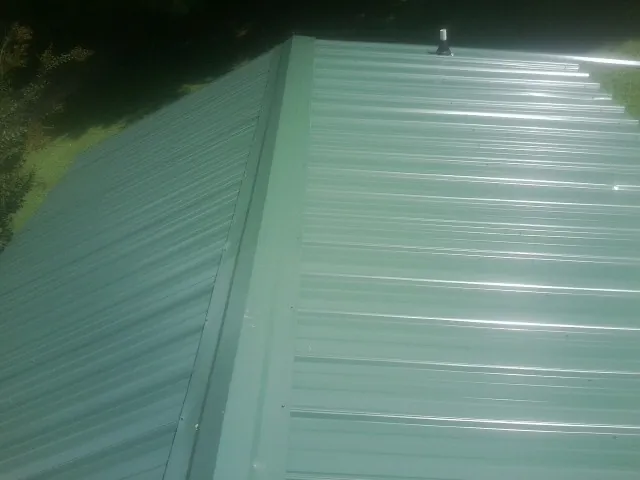New green metal panels meeting at the ridge of a roof — Flat Roof Repair work by our crew in Stevens