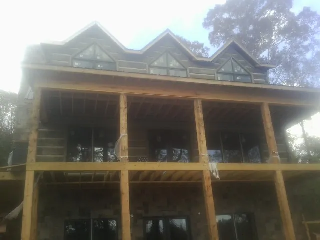 Dormers and porch framing on a large log home under construction — Roof Coating work by our crew in Stevens