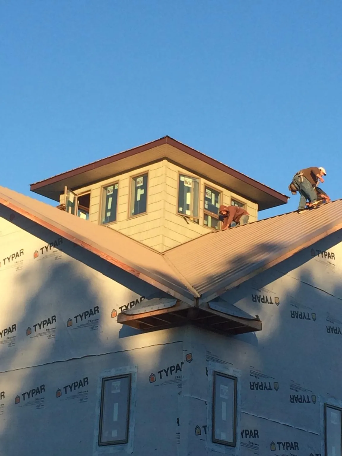Roofers working around a rooftop cupola on a new metal roof at sunset — Roof Waterproofing in Stevens by Roofing Brothers